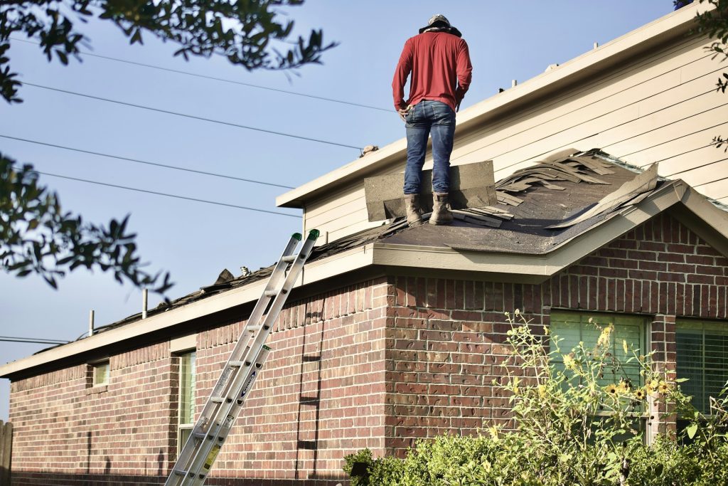 Roofer inspecting the roof of a brick home