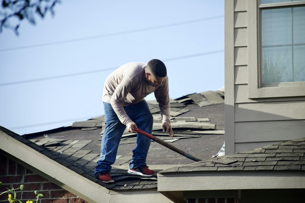 Roofer tearing off old shingles